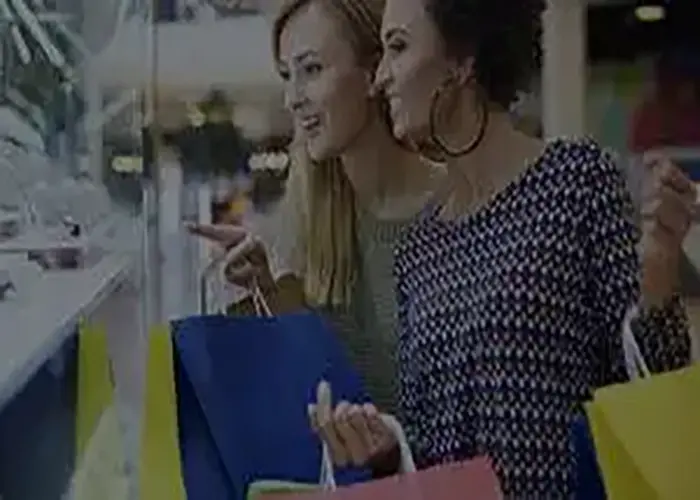 Two women shopping for consumer products in a retail store, holding colorful shopping bags and examining items on display. The image represents Ambit Software’s launch of a Consumer Durables Extension for Field Service Management on SugarCRM.