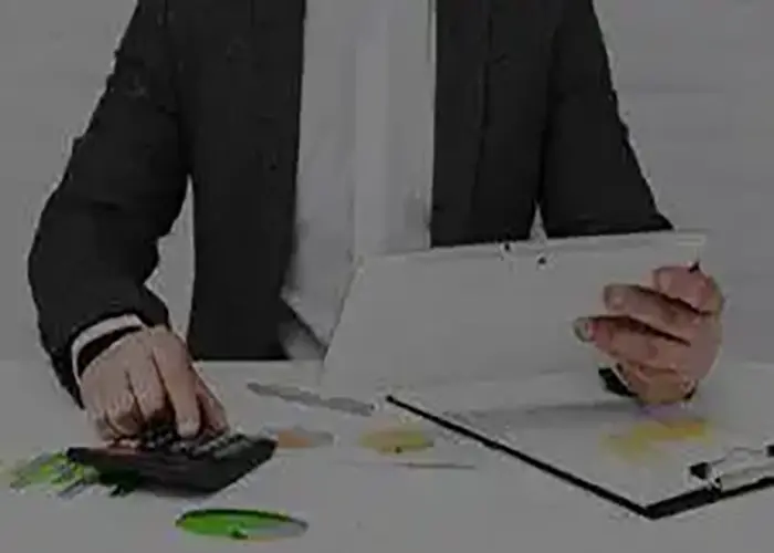 Business professional reviewing financial documents and using a calculator to analyze business costs and pricing